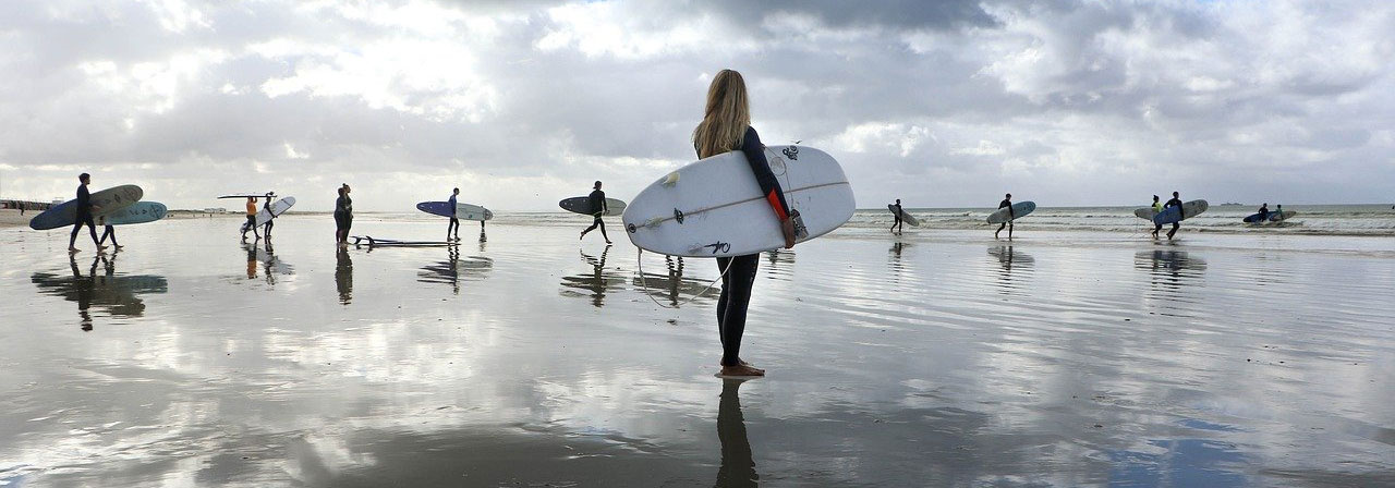 many surfers standing in sand